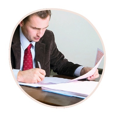 A person reading and writing on a stack of documents.